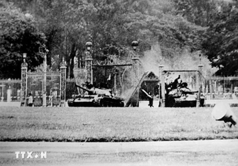 Tank T59 No 390 (left) crashes through the Independence Palace’s main gate at noon of April 30, 1975. (Photo: Francoise de Mulder/VNA broadcasts)