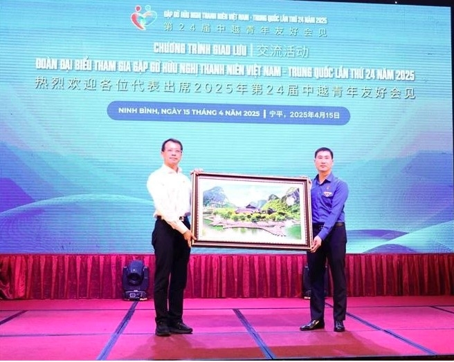 Secretary of the Ninh Binh provincial Youth Union Trinh Nhu Lam (right) presents a painting of the Trang An landscape to a representative of the Chinese youth.