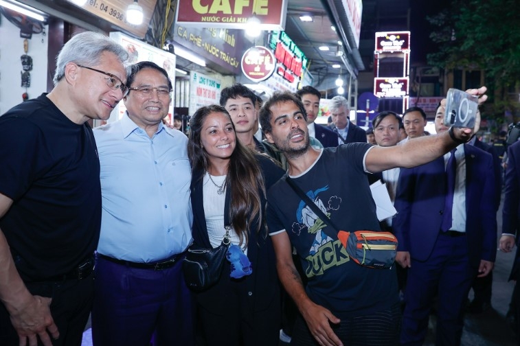 Prime Minister Pham Minh Chinh and Jensen Huang, president and CEO of Nvidia, pose for a photo with tourists at the Old Quarter in Hanoi on December 5, 2024. (Photo: Doan Bac)