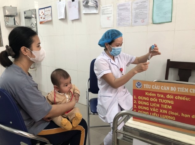 A medical staff administers measles vaccine to a small child (Photo:cand.com.vn)