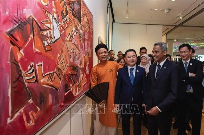 Vietnamese artist Nguyen Tuan Son (left) tell visitors about his paintings at the exhibition.