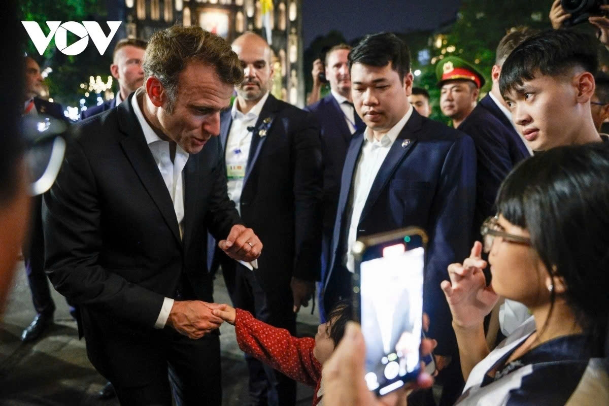 The French President enthusiastically chats with local residents while strolling through Hanoi's Old Quarter.