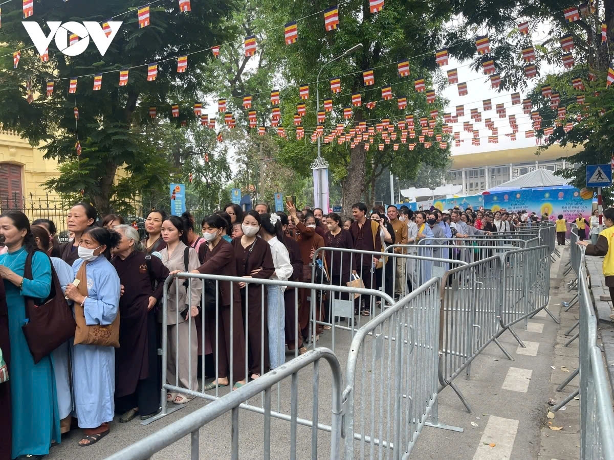 Dressed in respectful attire, devotees stand in long, orderly lines, moving step by step toward the pagoda.
