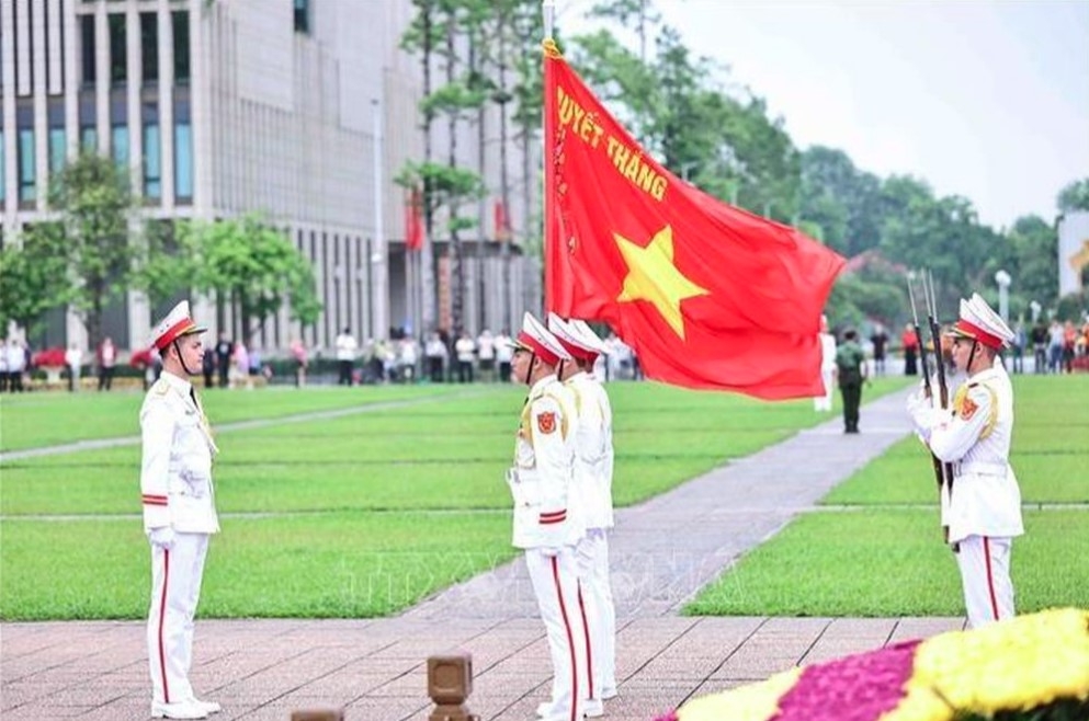 Three soldiers holding the red flag stand solemnly ready to step onto a podium for the ceremony.