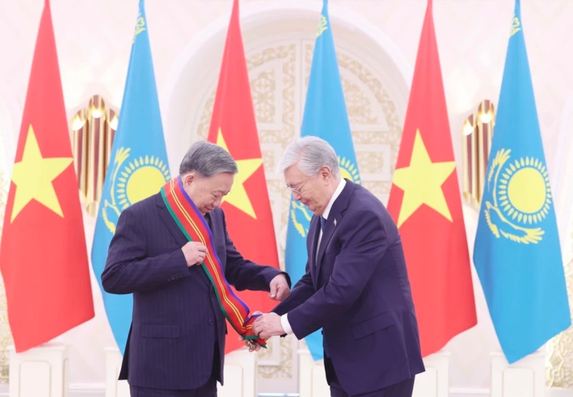 Kazakh President Kassym-Jomart Tokayev (R) presents the Order of Dostyk of the First Class to Party General Secretary To Lam.
