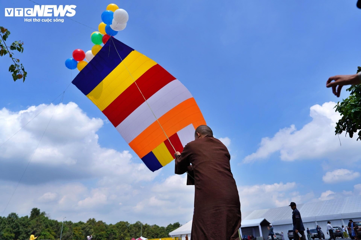 The giant Buddhist flag, a sacred symbol of Buddhism, ascends into the clear blue sky