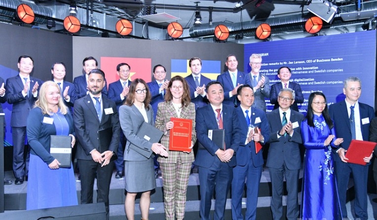 PM Pham Minh Chinh, Swedish officials witness the exchange of cooperation documents between Vietnamese and Swedish firms at the forum (Photo: nhandan.vn)