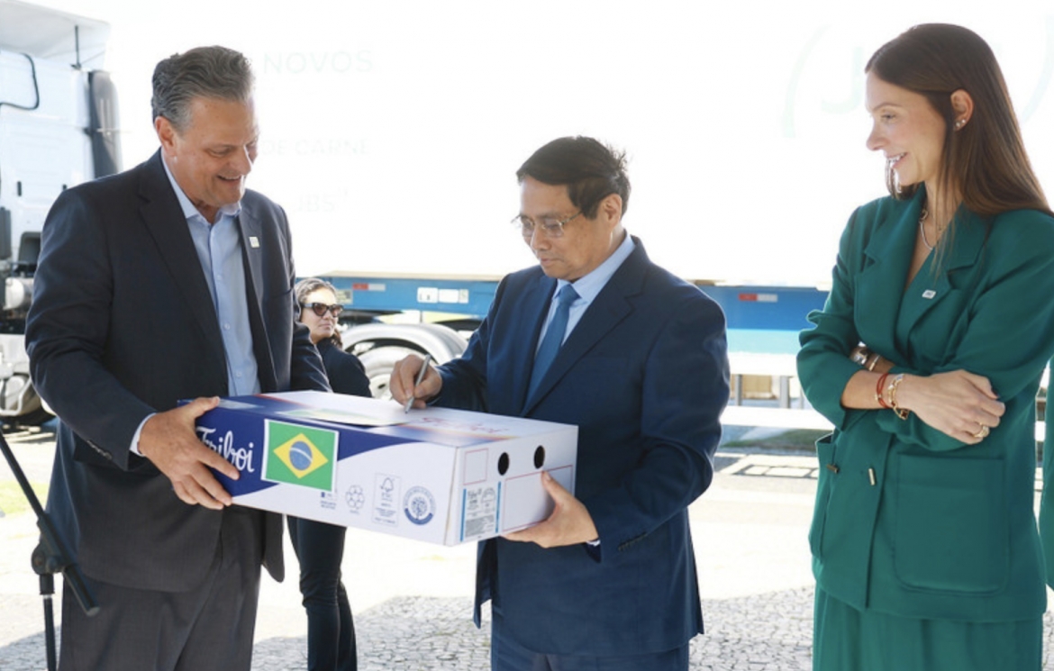 PM Pham Minh Chinh (C) signs on a pack of beef exported to Vietnam. (Photo: VNA)