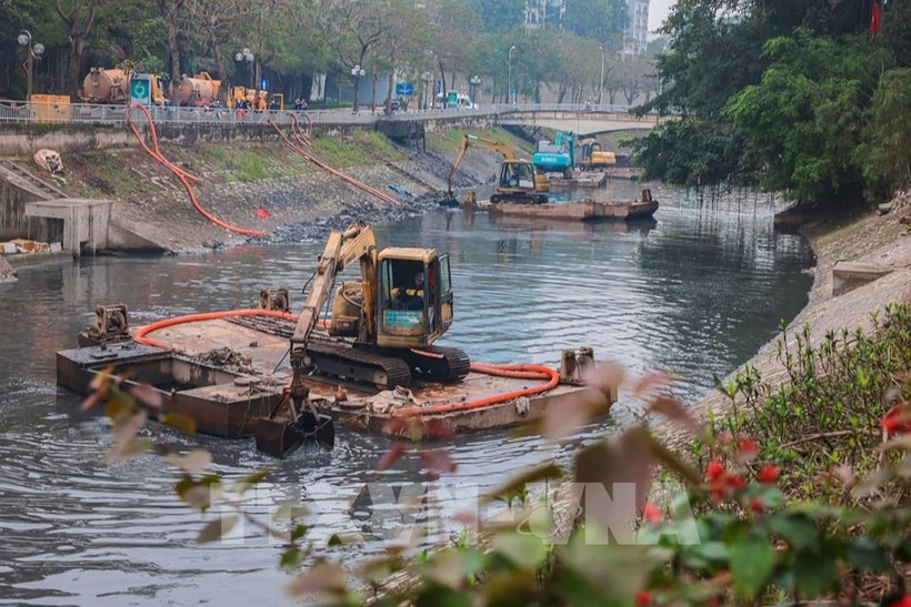 Vehicles and equipment are deployed to dredge a river in Hanoi.