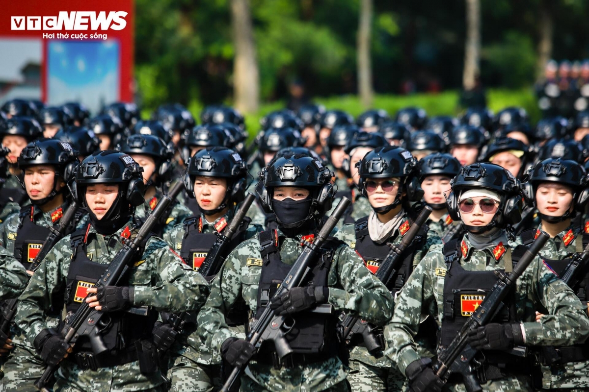 The female special task force stands out prominently on the training ground, dressed in sleek, form-fitting digital camouflage uniforms in olive green. They wear black helmets equipped with specialized radios, soft body armor on their shoulders, and firmly hold MP5 submachine guns commonly used in counter-terrorism and hostage rescue missions.