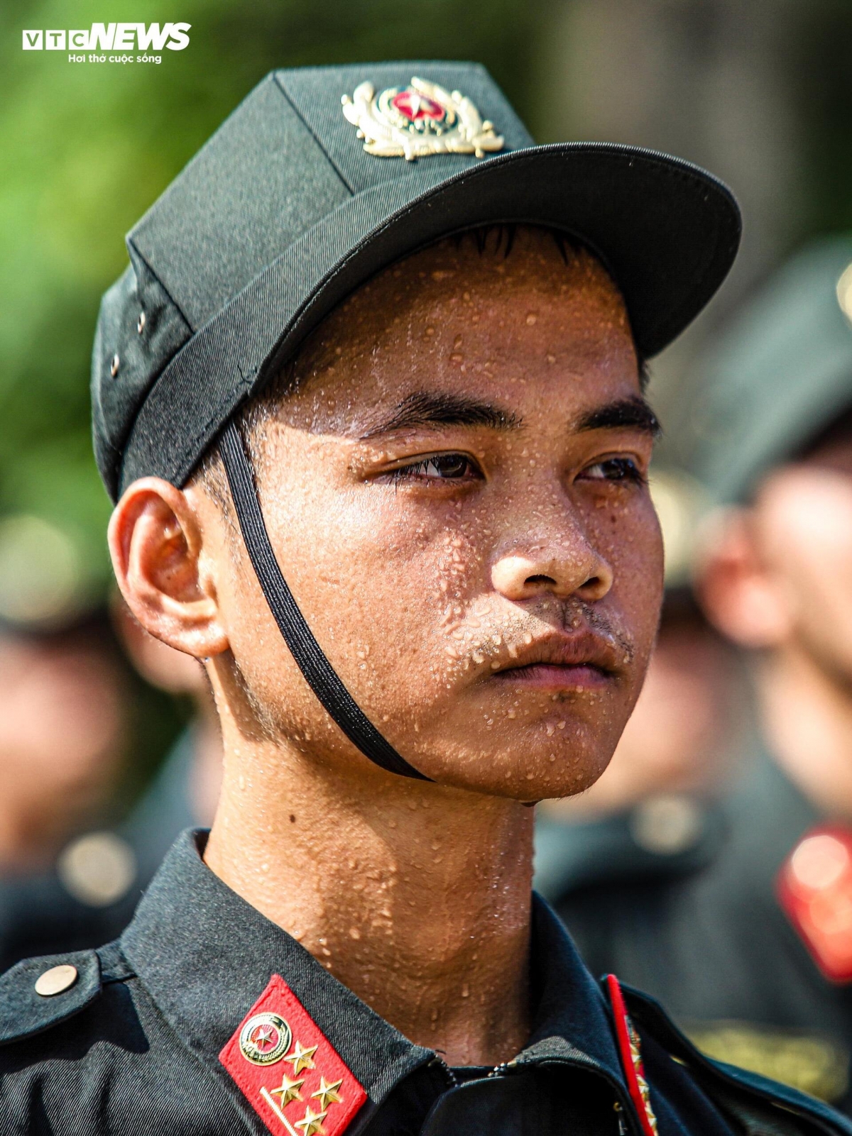 Sweat stream down the face of a male mobile police officer under the blazing sun, highlighting the harsh weather conditions he endures during the training session.