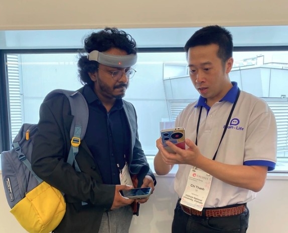 Brain-Life CEO Vi Chi Thanh (right) shows a customer how to use the Focus+ mental health device
(Photo: thanhnien.vn)
