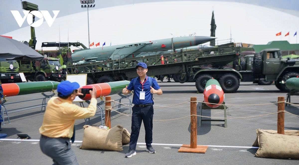 Visitors to the largest-ever exhibition excitedly take photos with the backdrop of training torpedoes and missiles on display. The outdoor exhibition area carries the theme “The Sword and the Shield.”