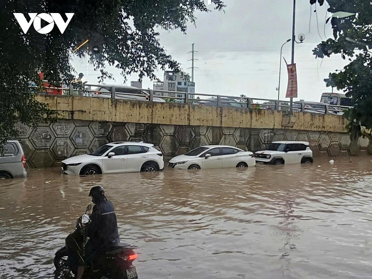 At the Yen Nghia overpass in former Ha Dong district, many vehicles have to divert into small alleys to avoid deeply flooded sections.