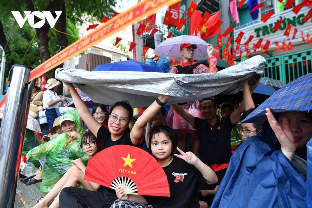 Residents at the Kim Ma – Nui Truc intersection hold their spots with umbrellas and raincoats, while many take shelter in public tents from the rain.