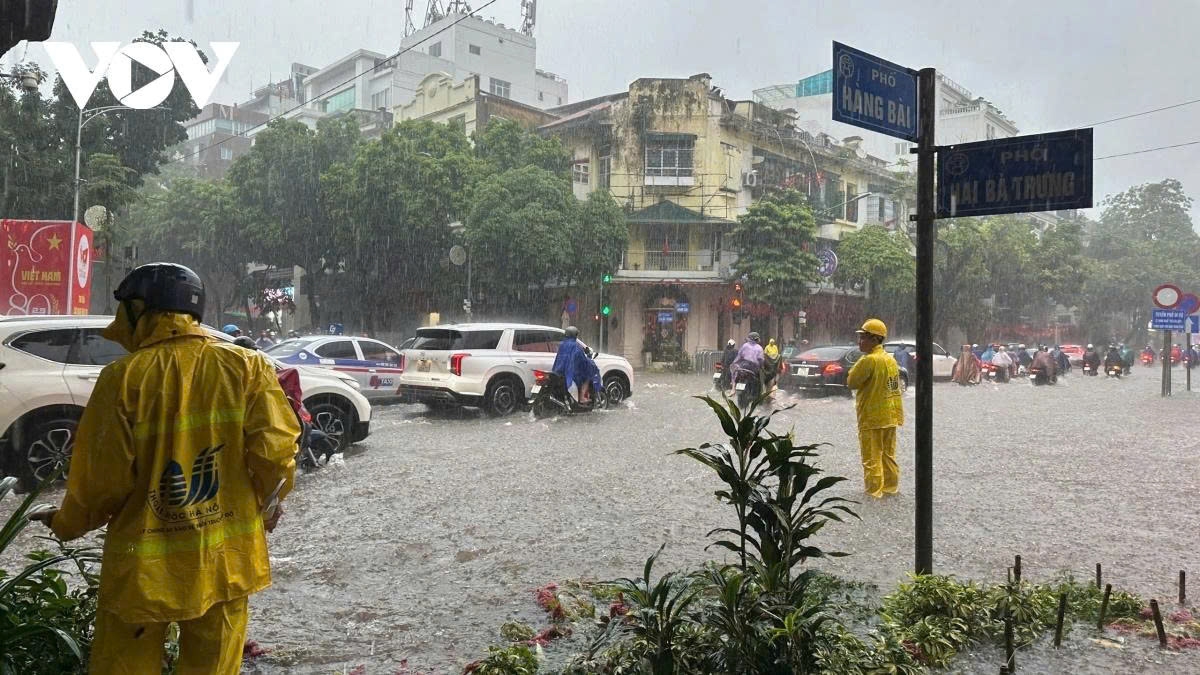 Hanoi Drainage Company workers are stationed at flooded points to open manholes and accelerate water drainage.
