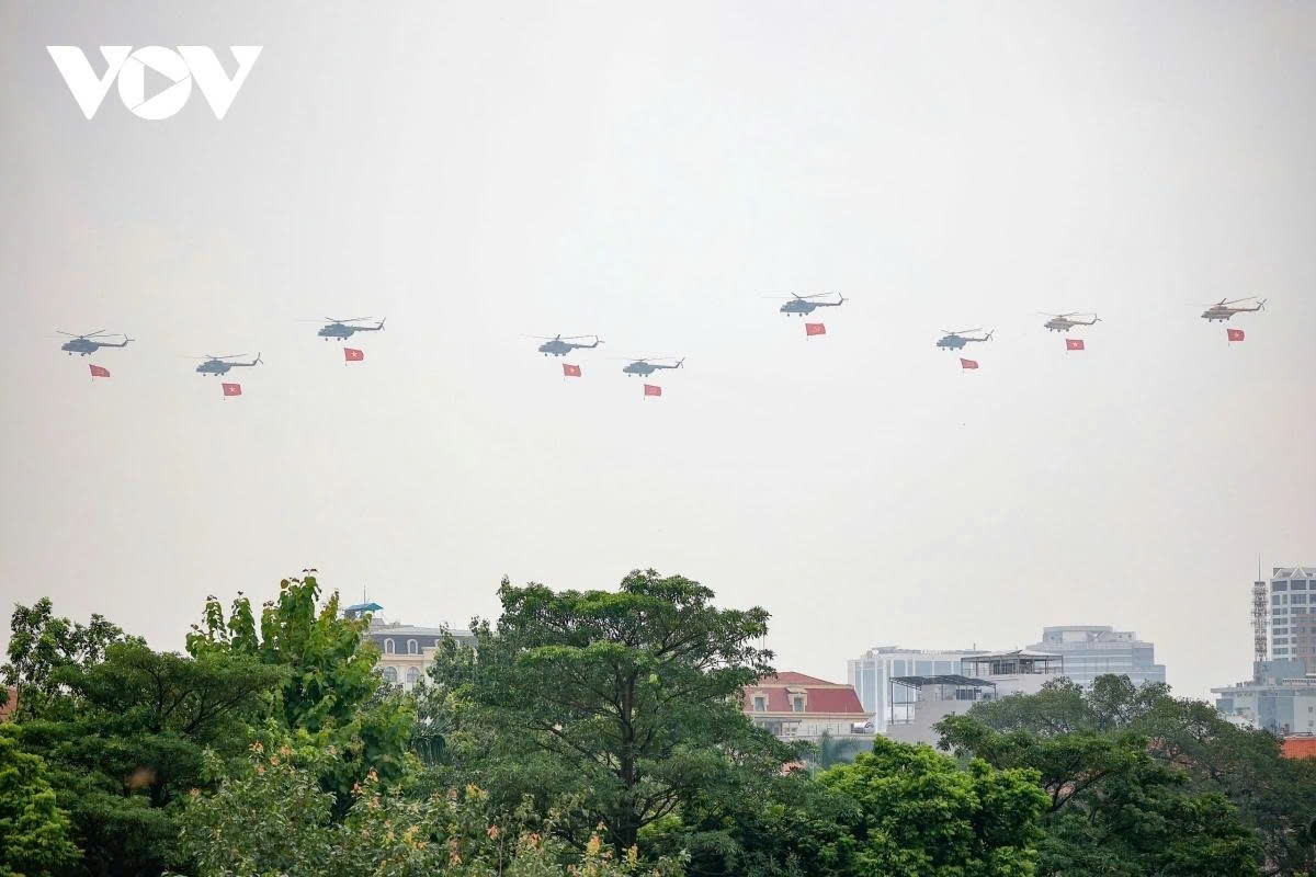 Helicopters carrying the Party flag and the national flag fly in formation over the Hanoi sky on the morning of August 28.