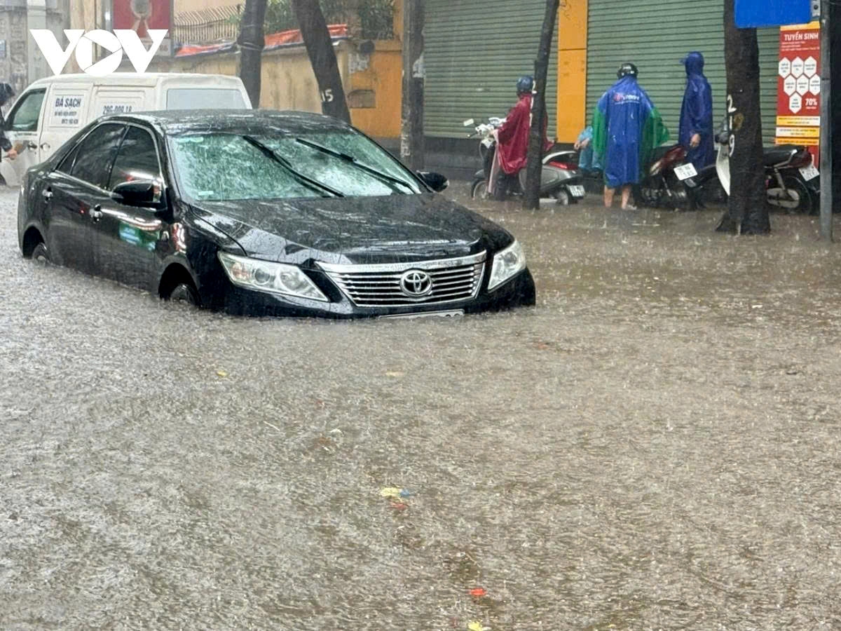 On Thai Thinh Street, floodwaters rise almost to the tops of vehicle wheels, leaving commuters struggling to pass.