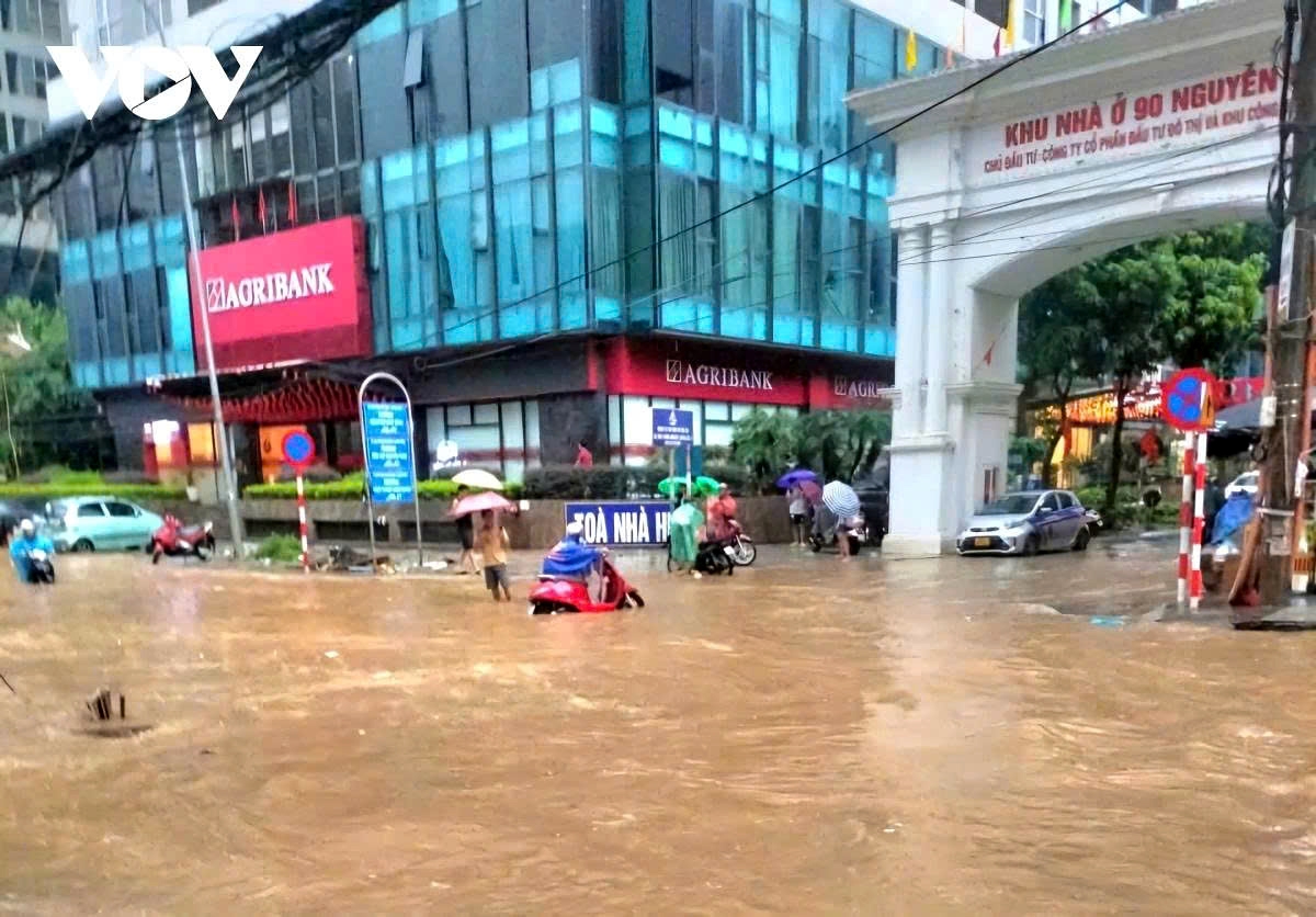 Kajiki dumps 400–500mm on Nguyen Tuan Street in former Thanh Xuan District, forcing motorcyclists to push their bikes, and residents to wade through waist-deep water.