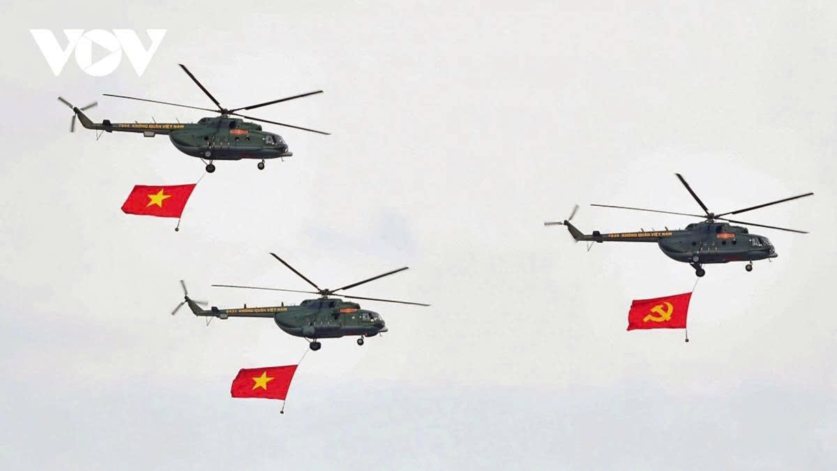 A formation of 10 military helicopters fly over central Hanoi, passing above Ba Dinh Square and carrying the Party flag and the national flag.