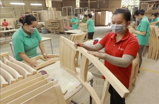 Workers make wooden furniture for export to the US, UK and EU markets at the factory of the Thiet Dan Two-Member Company Limited. (Photo: VNA)