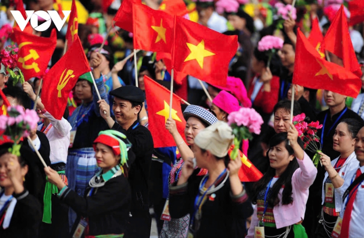 Civic groups wave flags and flowers as they march past Ba Dinh Square