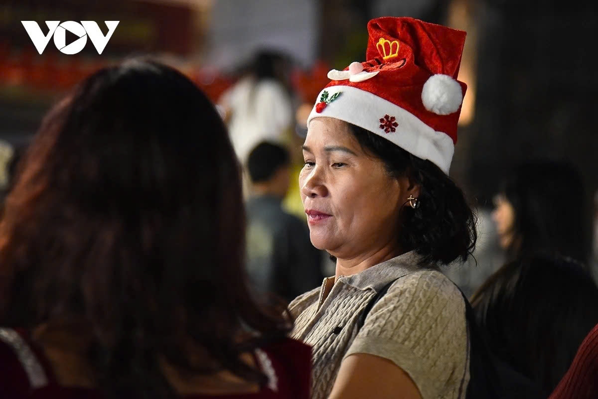 Residents and visitors wearing Christmas-themed attire enjoy the festive atmosphere on the Hoan Kiem Lake pedestrian street.