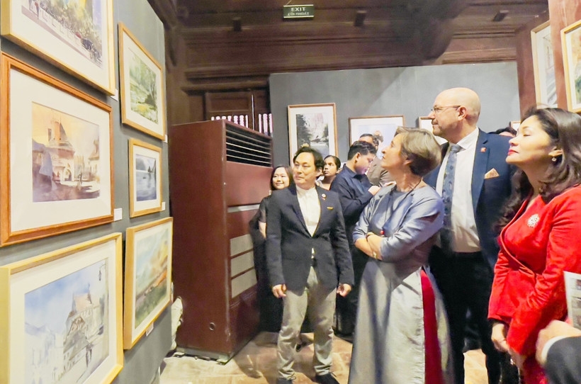 Painter Minh Dam introduces his works to visitors at the exhibition. (Photo: VNA)