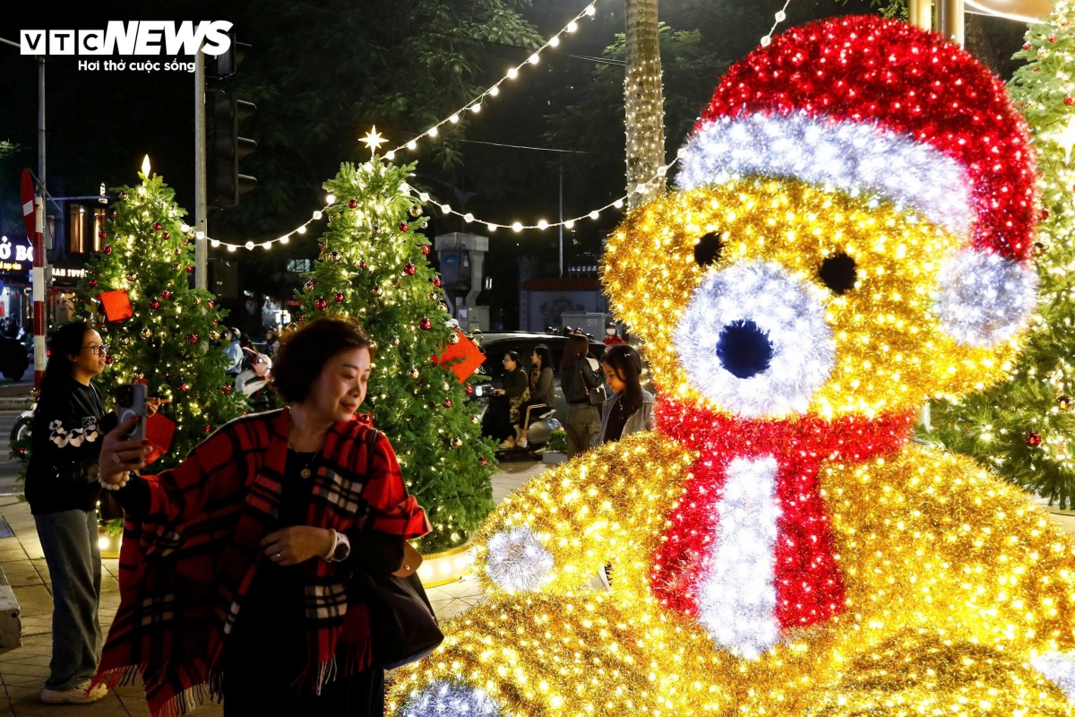 A Christmas teddy bear crafted from thousands of lights attracts many visitors eager to take photos.
