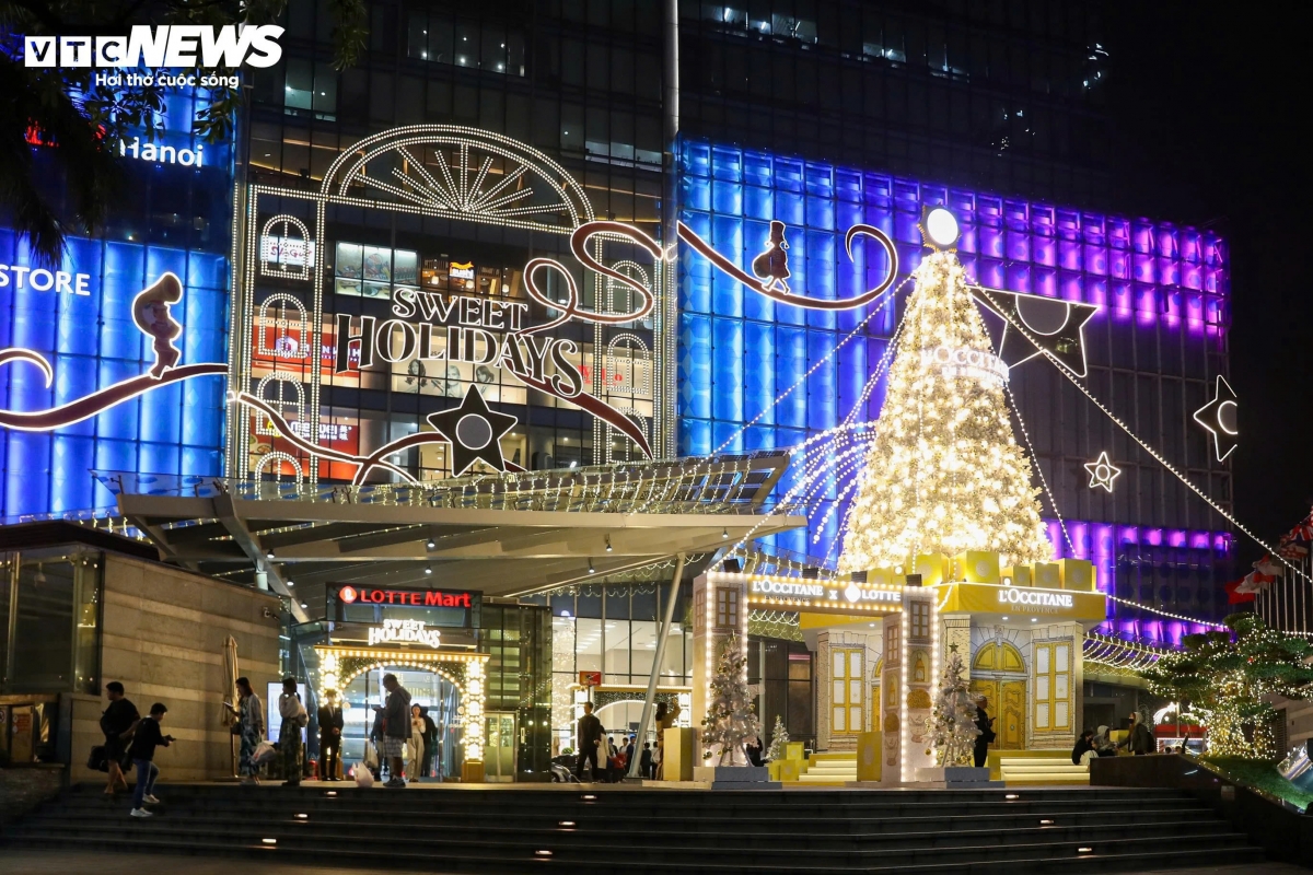A giant Christmas tree stands in front of Lotte Center Hanoi, perched on a brightly colored gift box, lighting up a corner of the street.