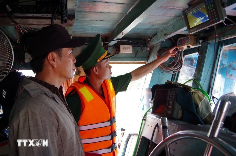 A border guard officer of Dong Thap examines the operation of the vessel monitoring system on a fishing boat.