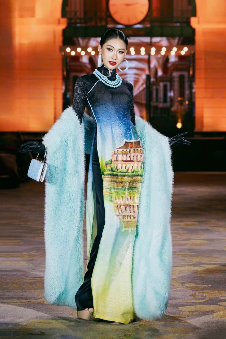 Architectural works and scenery spots in the world are introduced in each outfit. In the photo, Miss Cosmo Vietnam 2025 Nguyen Hoang Phuong Linh captures the attention with Ao Dai (traditional Vietnamese long dress) featuring an image of Nha Rong Wharf.