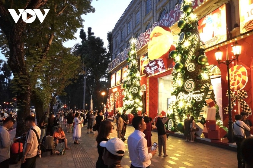 Two large Christmas trees adorned with bright decorations at a shopping mall