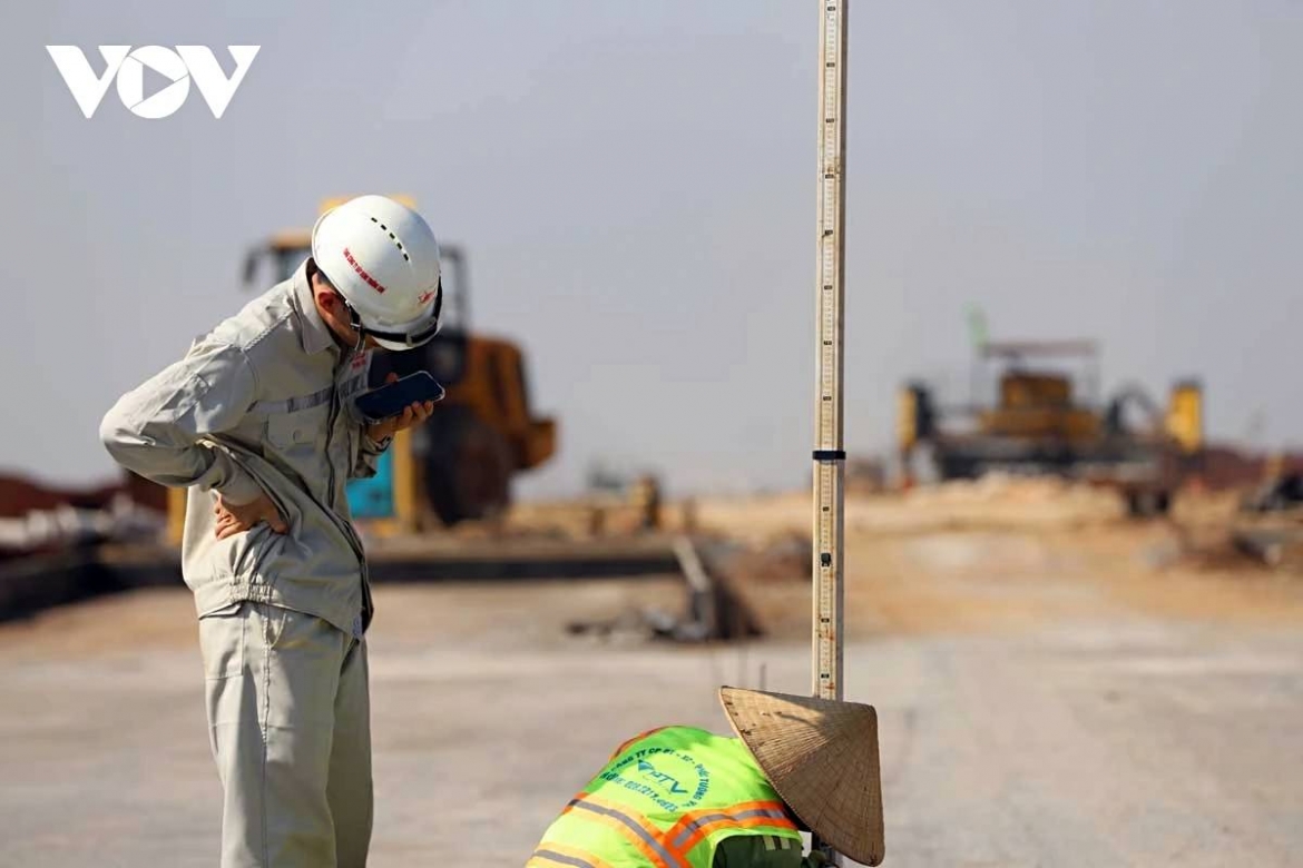 Surveying engineers stand under the scorching sun at the Long Thanh airport site, keeping instruments steady to ensure technical accuracy.