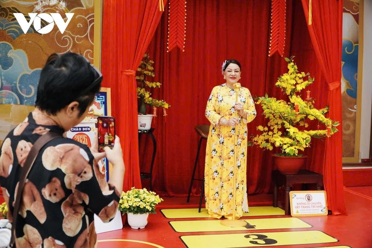 People wearing Ao Dai (traditional long dress) take a photo with the Tet-themed decorations.