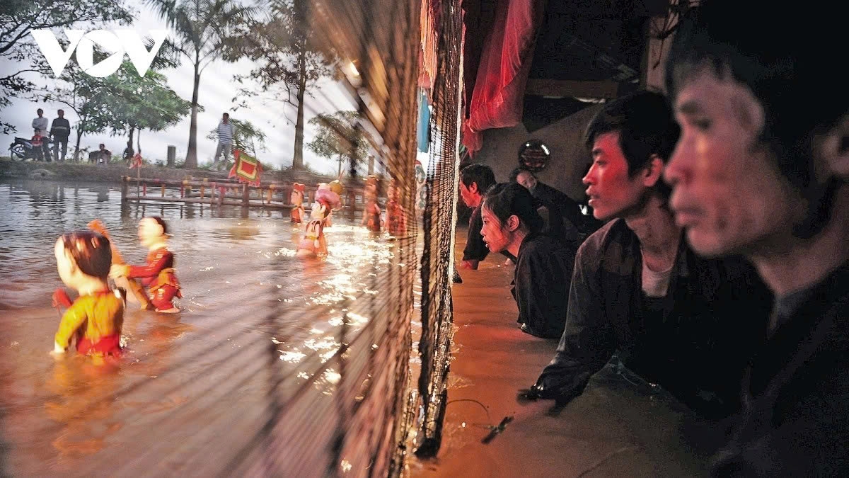 Behind bamboo screens, puppeteers stand waist-deep in water, manipulating brightly lacquered wooden figures using hidden rods and strings beneath the surface
