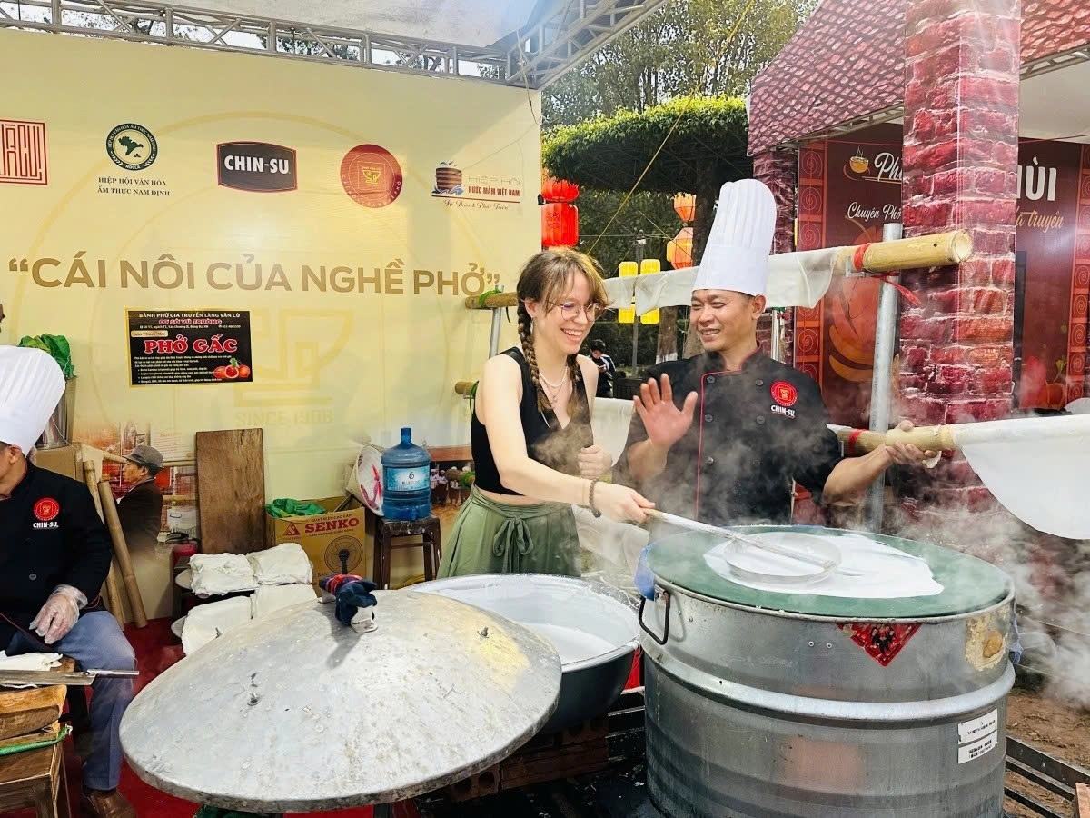 A foreign visitor tries making traditional rice papers for phở at the 2025 Phở Festival