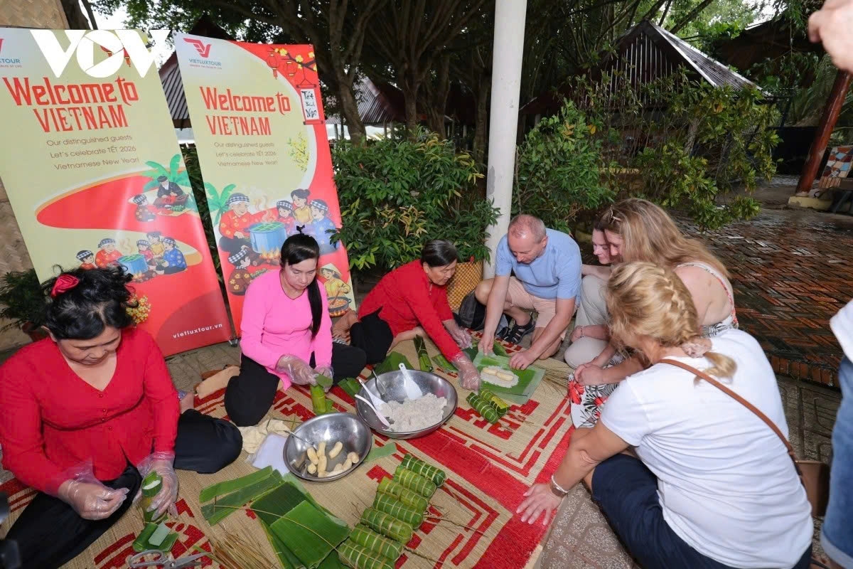 Foreign visitors enthusiastically join locals in making bánh tét for the Tet holiday