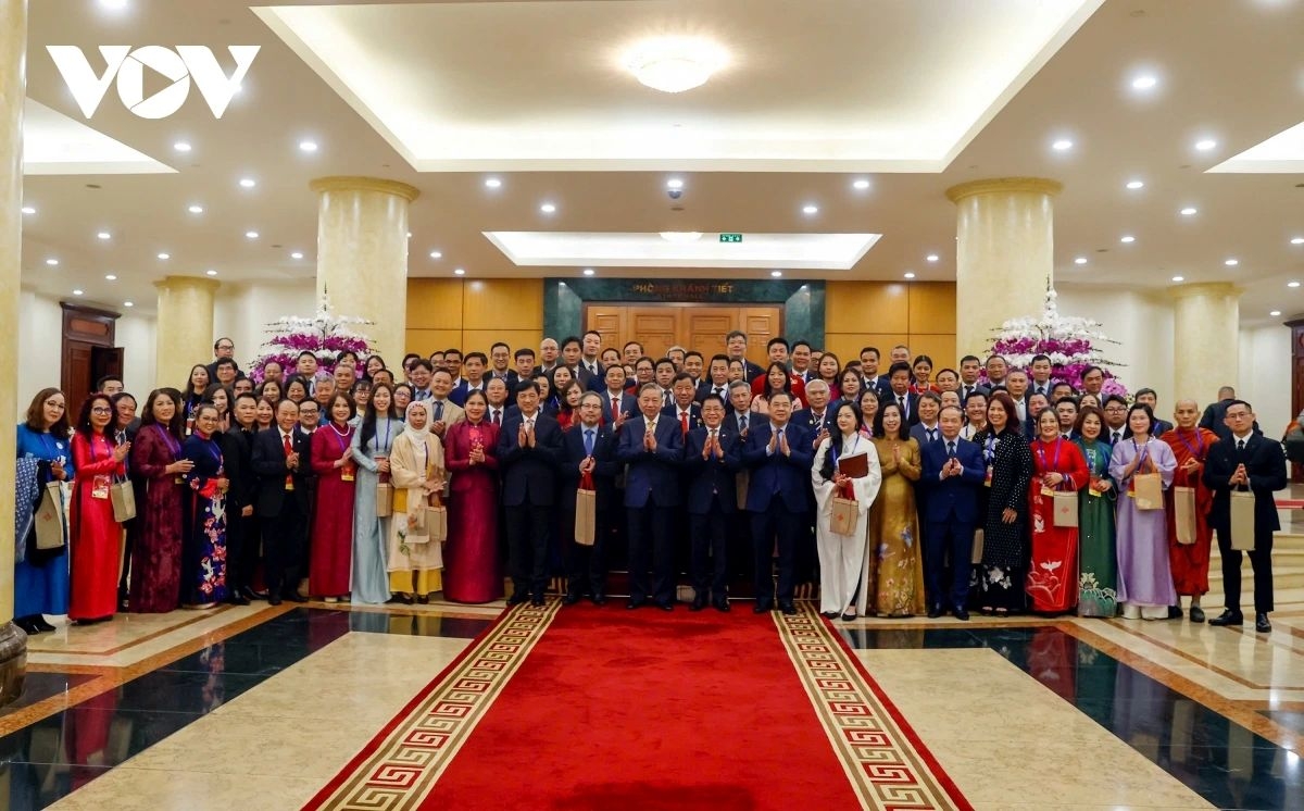 Party General Secretary To Lam and overseas Vietnamese returning home for the Lunar New Year holiday pose for a group photo