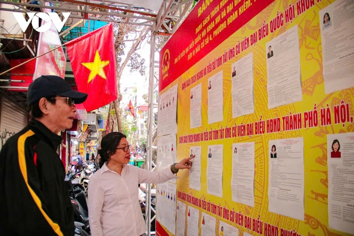 Inside the historic Kim Ngan communal house on Hang Bac Street in Hoan Kiem district, election information boards are placed within the heritage site alongside national flags and posters.