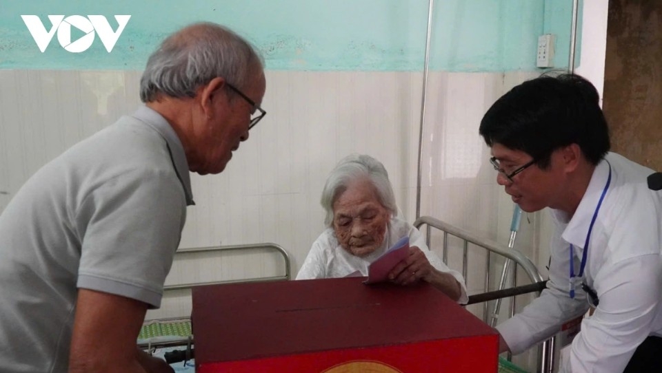 Dang Thi Lam, 116, from Thach Bo village in Hoa Vang commune of Da Nang, is unable to travel to the polling station due to health reasons. With a mobile ballot box brought to her home and guidance from polling station staff, she carefully casts her vote.