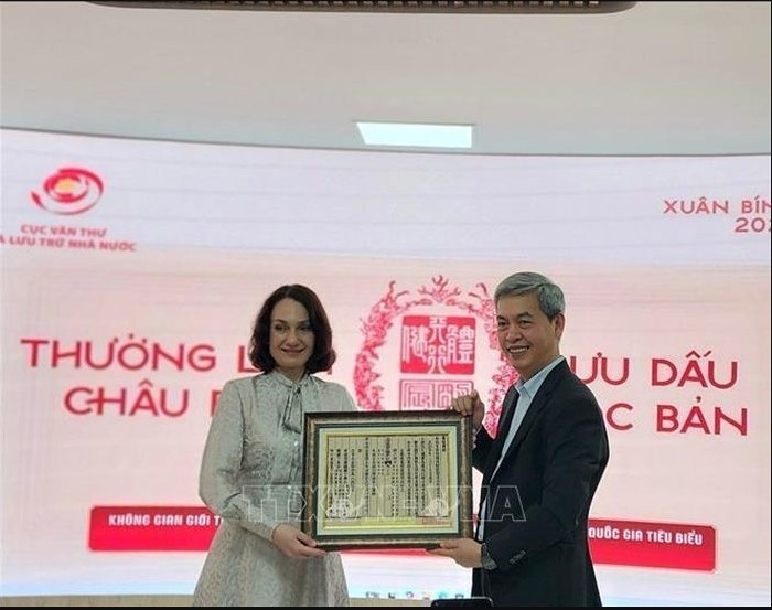 Director of the State Records and Archives Department of Vietnam Dang Thanh Tung presents Elena Bezdetko, spouse of the Russian Ambassador to Vietnam, with a woodblock print of Vietnam’s national title