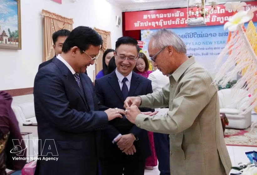 Phonesy Bounmixay (right), Lao Consul General in Ho Chi Minh City, performs the traditional baci string-tying ceremony to offer New Year blessings to a member of the Ho Chi Minh City delegation on April 10, 2026. (Photo: VNA)