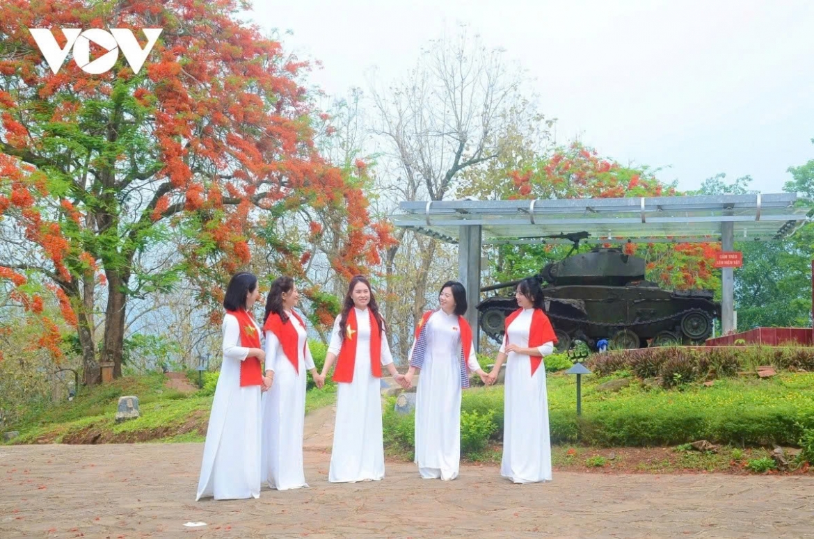 Young women in traditional Áo dài and national scarves pose beside a tank display at a historic site linked to the Battle of Dien Bien Phu, symbolising the connection between today’s youth and Vietnam’s wartime history.