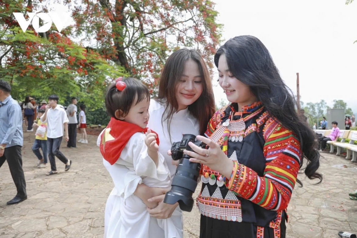 Children visit the historic site, posing for photos under vibrant flamboyant trees in full bloom.