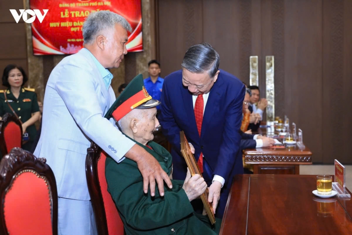 Party General Secretary and State President To Lam presents a certificate to a veteran Party member