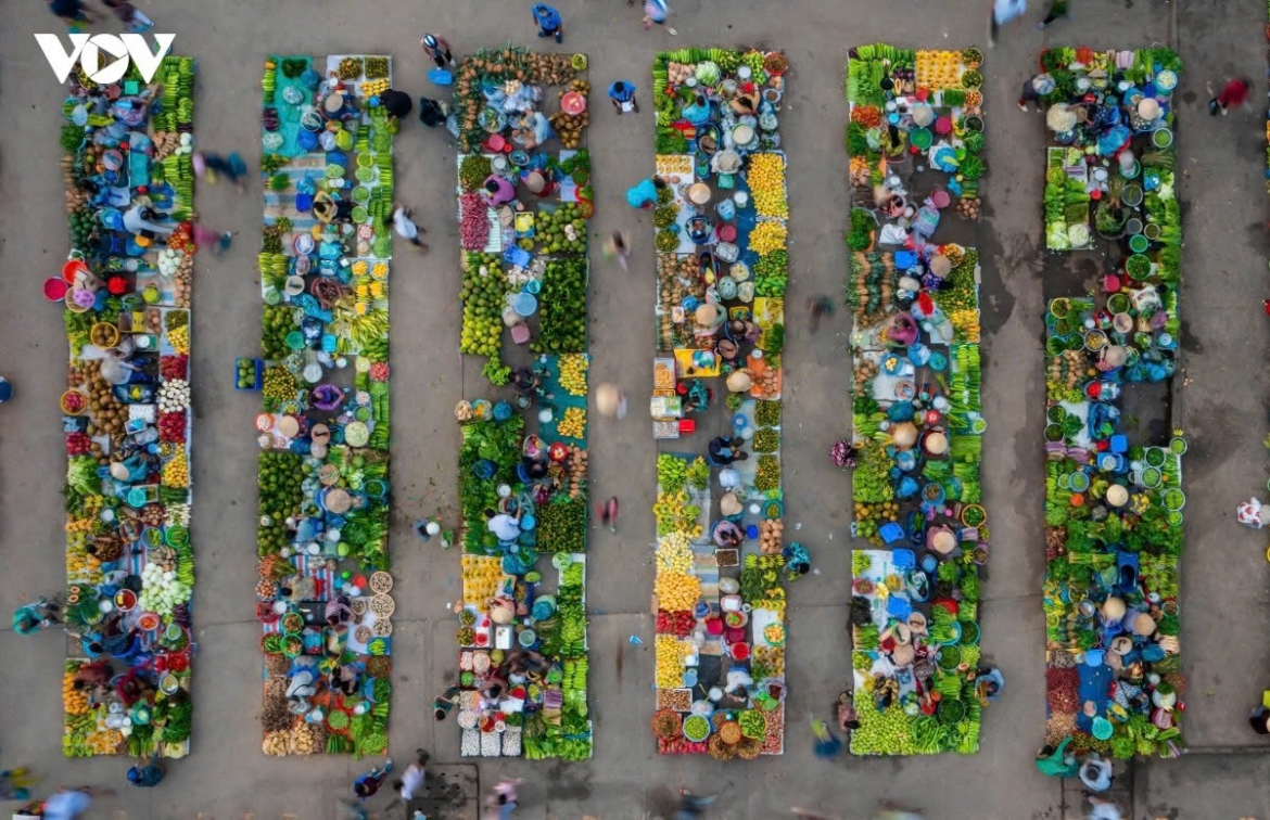 Rather than using tables or formal stalls, vendors typically display their goods on tarpaulins spread across the ground, while customers browse and negotiate from low stools or in a crouched position in an open-air setting.
