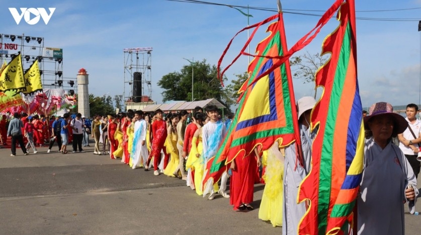Local youth carrying festival flags march along the Ca Ty River during the procession.